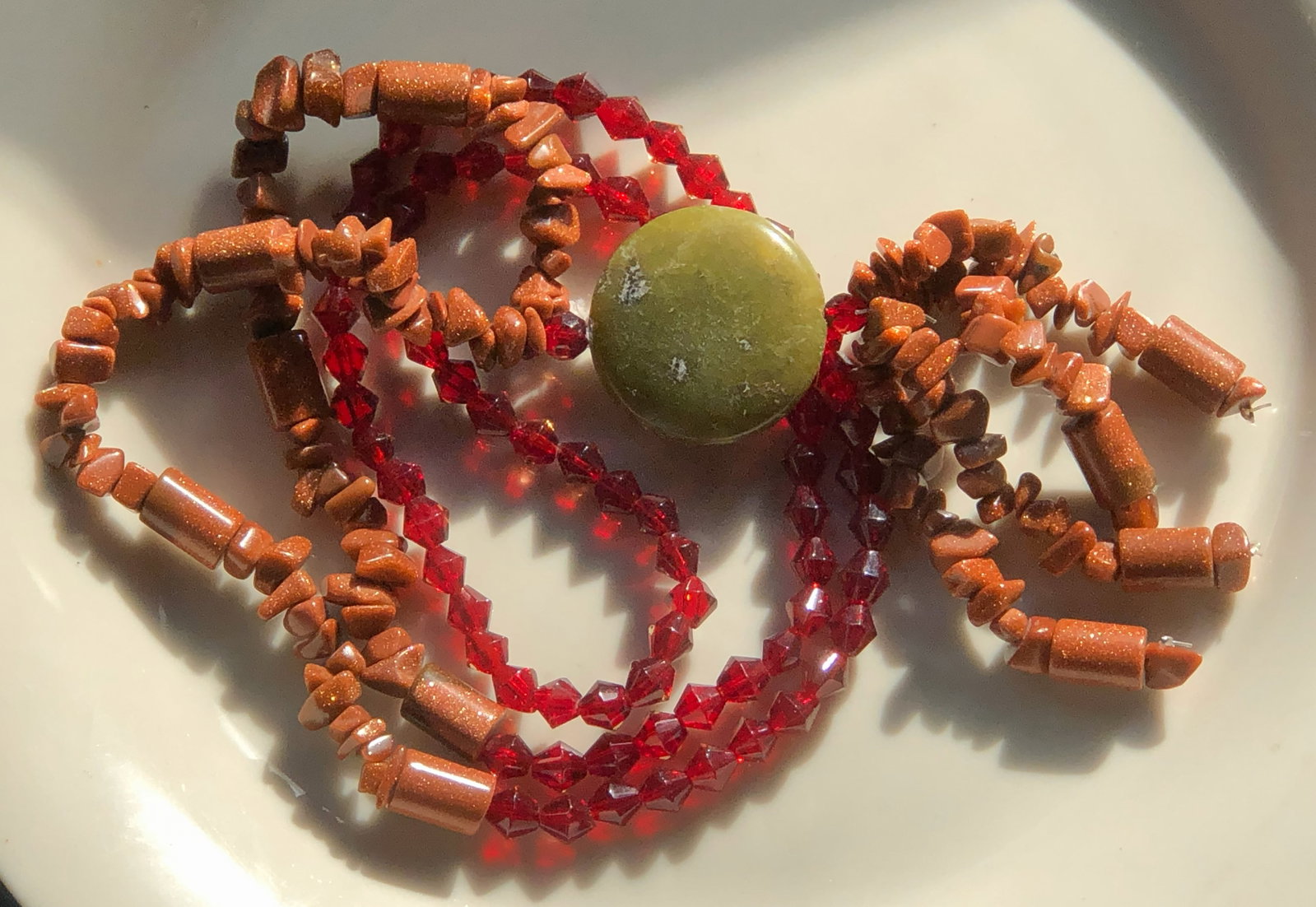 Handcrafted Beaded Necklace: A beautiful handcrafted necklace featuring red and brown beads with a central green stone.