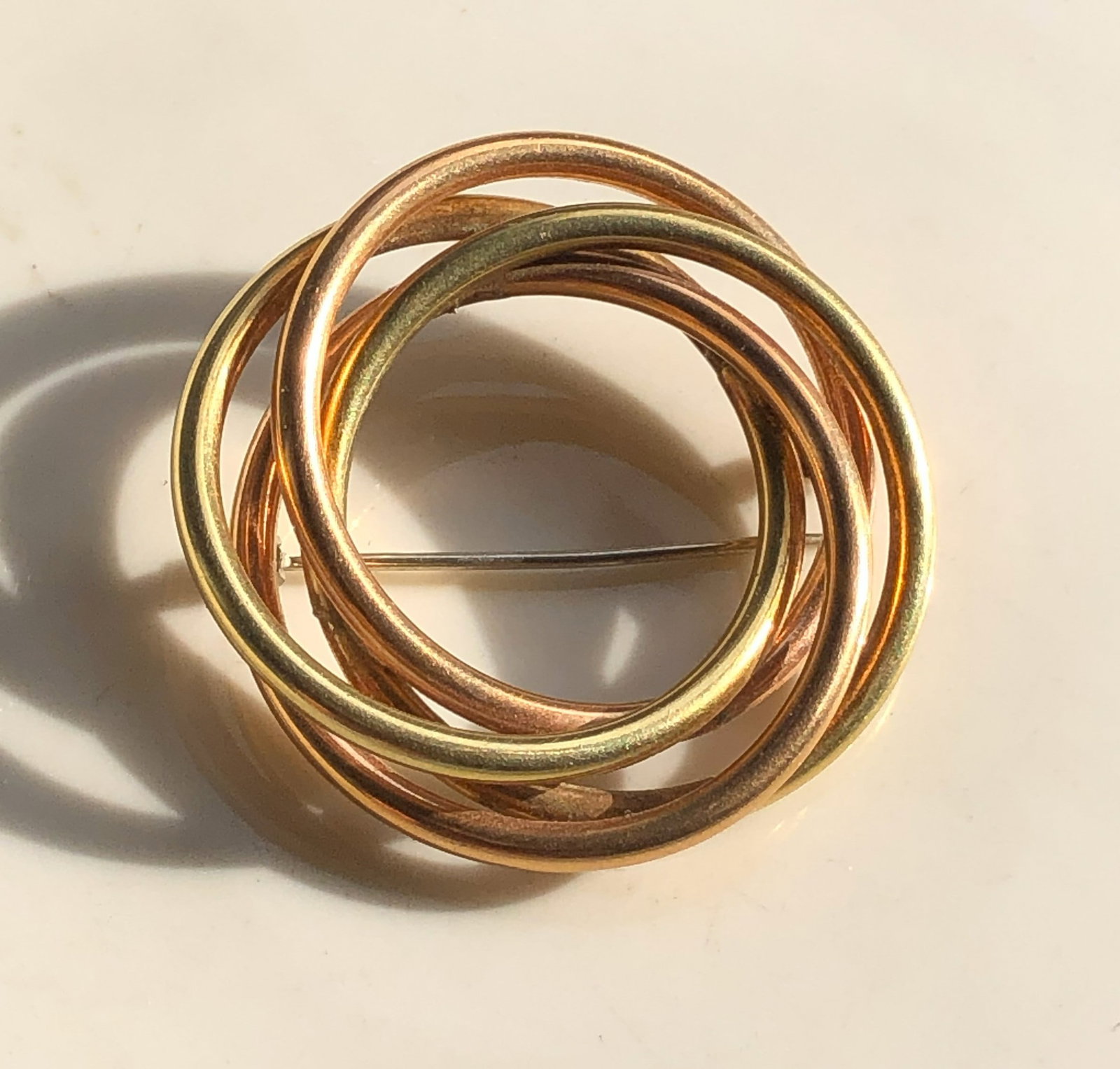 Gold and Copper color Brooch Pin: A stylish brooch made of intertwined gold and copper color rings.