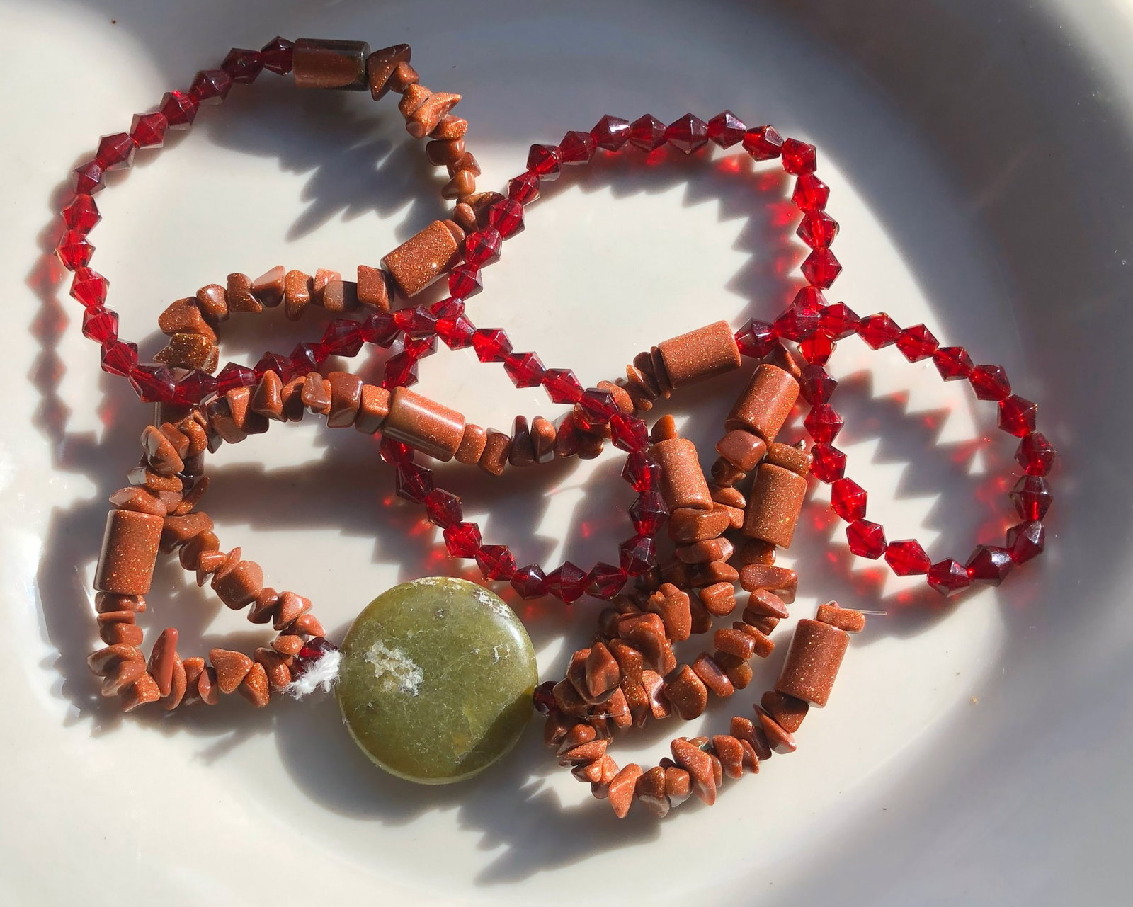 Beaded Necklace: A beautiful beaded necklace featuring red and brown beads with a unique stone centerpiece.