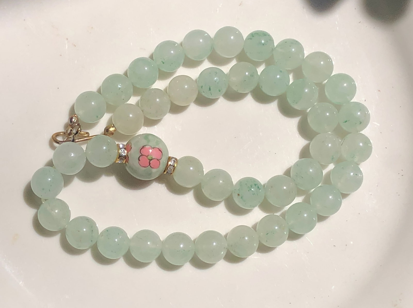 A beautiful jade bead necklace with a floral accent bead.: A beautiful jade bead necklace with a floral accent bead.