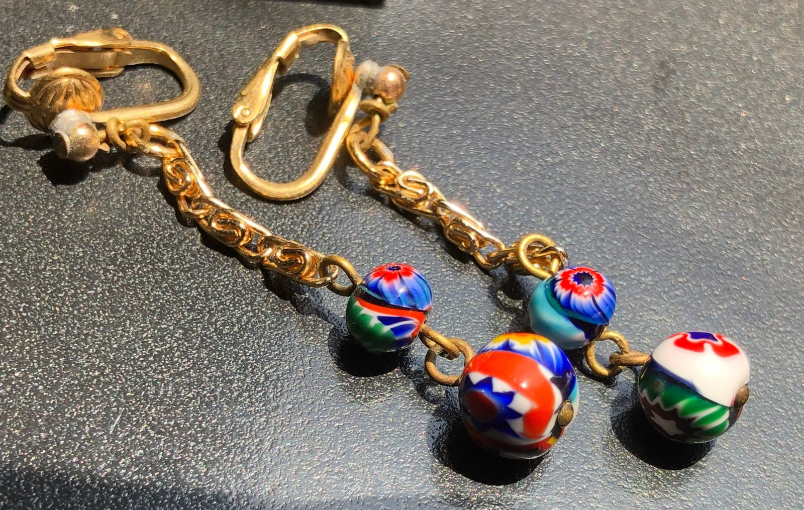 Elegant gold chain earrings with vibrant, multicolored beads.: Elegant gold chain earrings with vibrant, multicolored beads.