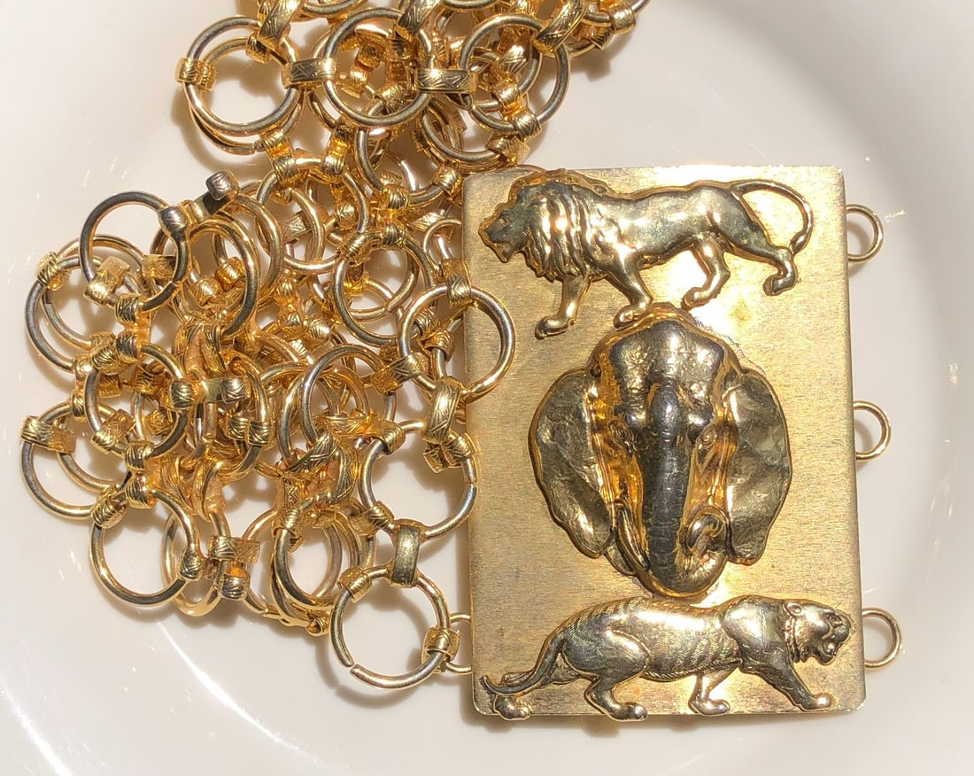 A luxurious gold color necklace featuring intricate animal motifs, including a lion, elephant, and (1 of 3)