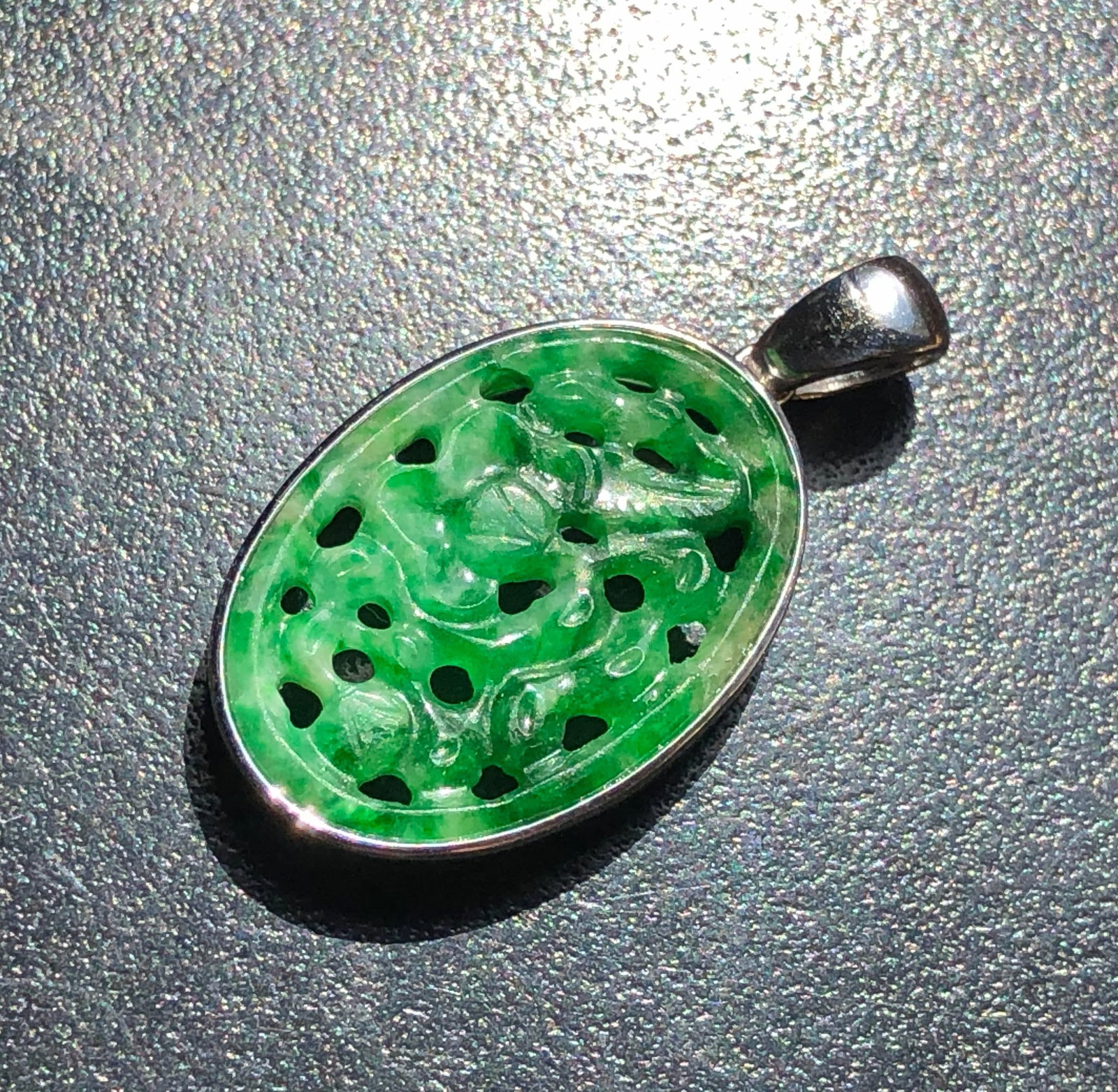Green Jadeite Pendant: A beautifully carved green jadeite pendant with intricate details, set in a silver frame.Size total: 1" x 0.8"