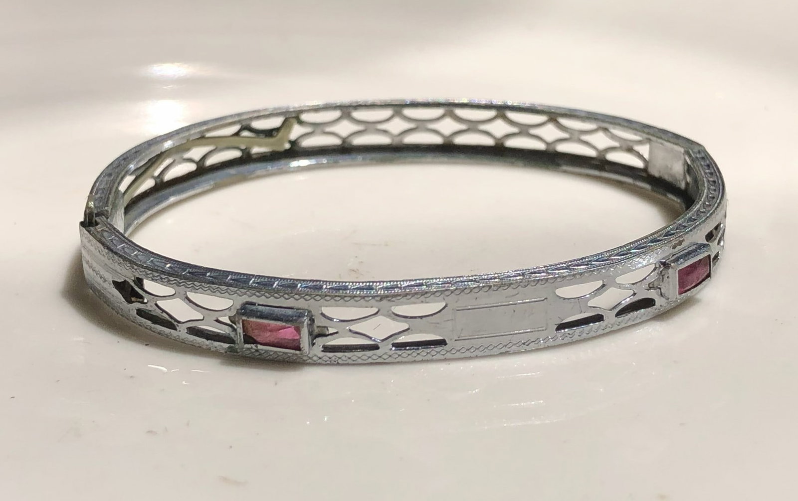Elegant bracelet featuring intricate cut-out designs and pink stones