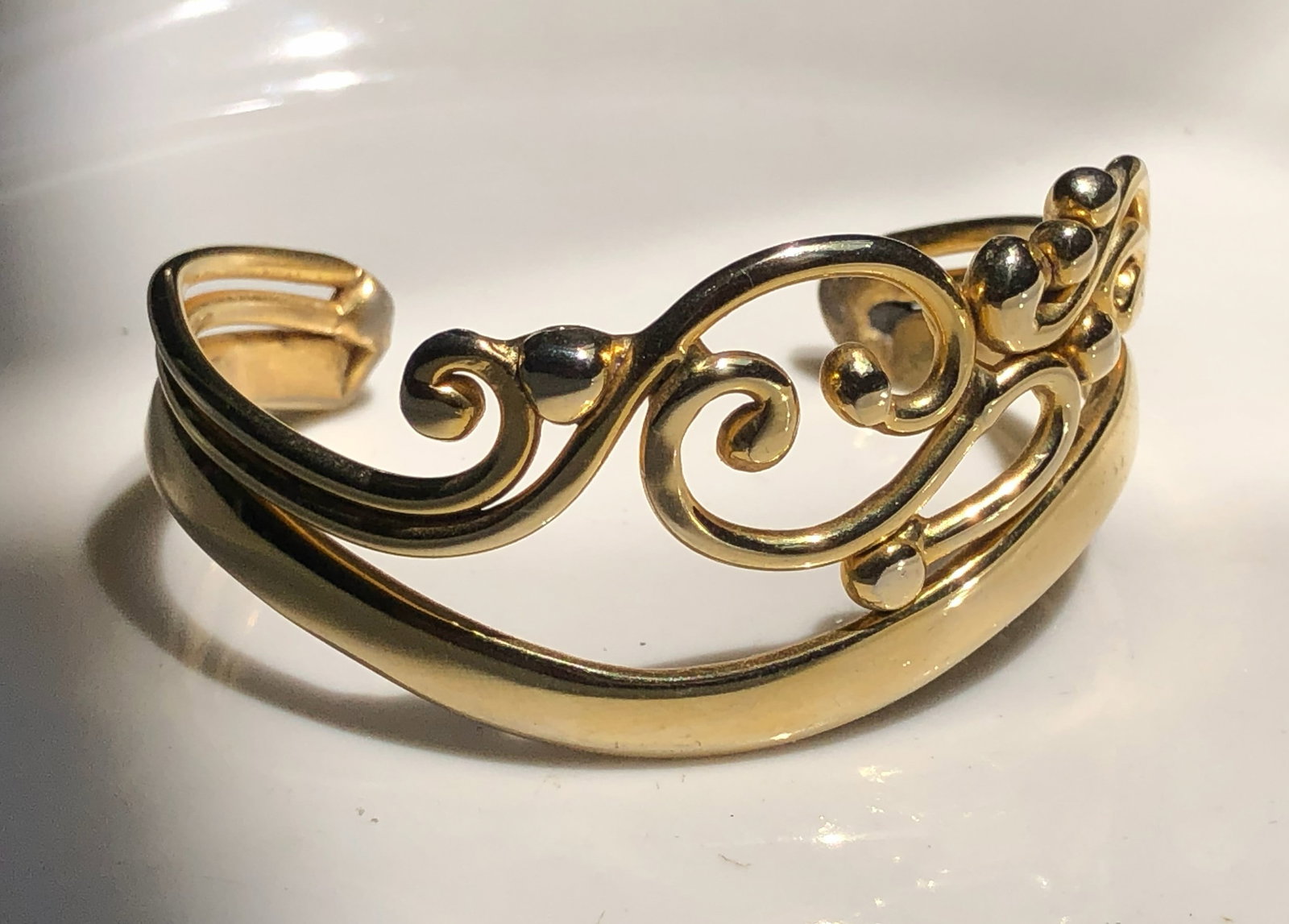 A beautifully crafted gold color bracelet with intricate swirl designs.: A beautifully crafted gold color bracelet with intricate swirl designs.