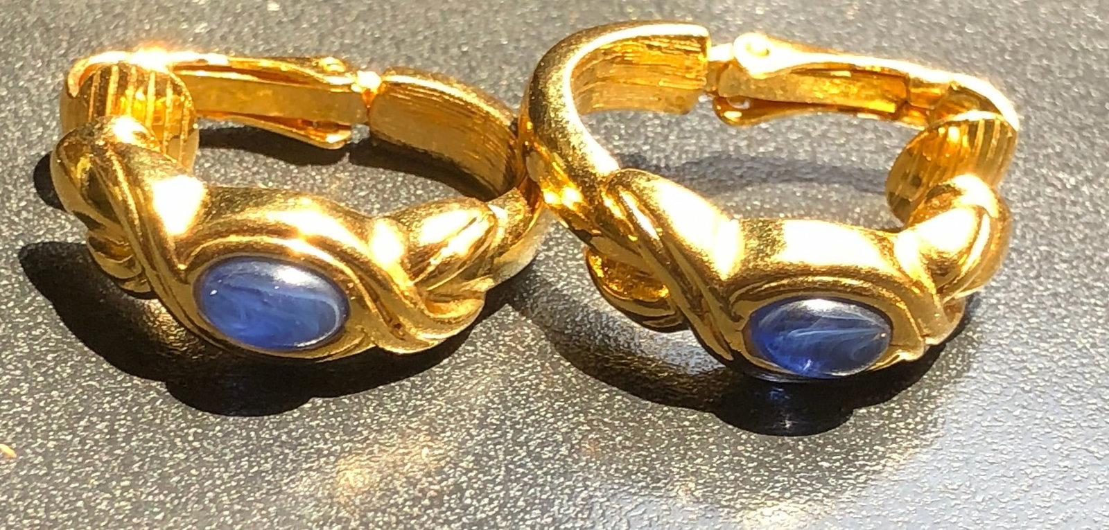 Elegant gold color earrings featuring a striking blue stone