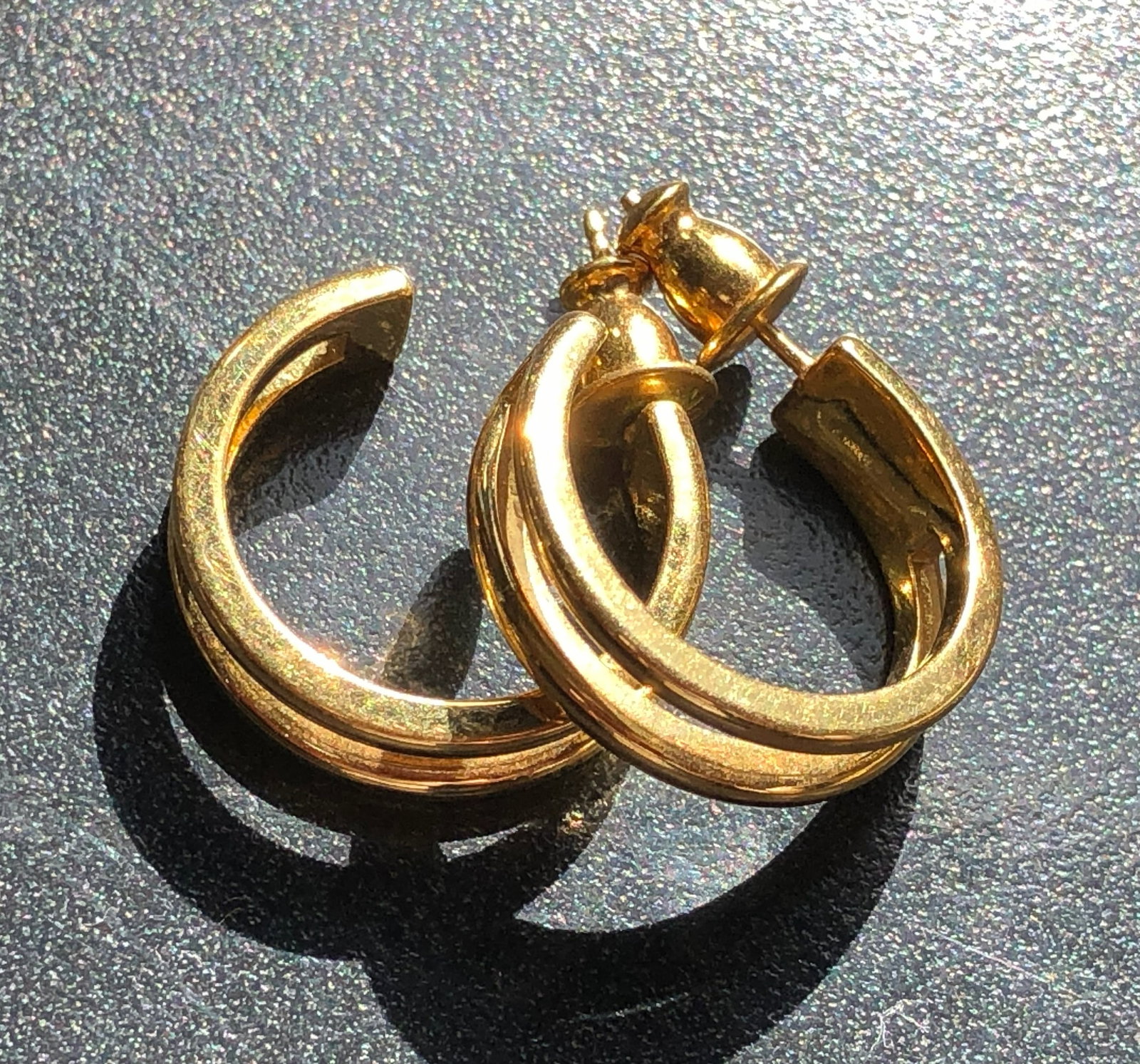 Gold Plated Sculptural Hoop Earrings: Pair of substantial gold-tone pierced hoop earrings formed from layered sweeping bands and fitted with post-and-clutch backs, showing light wear from previous use.