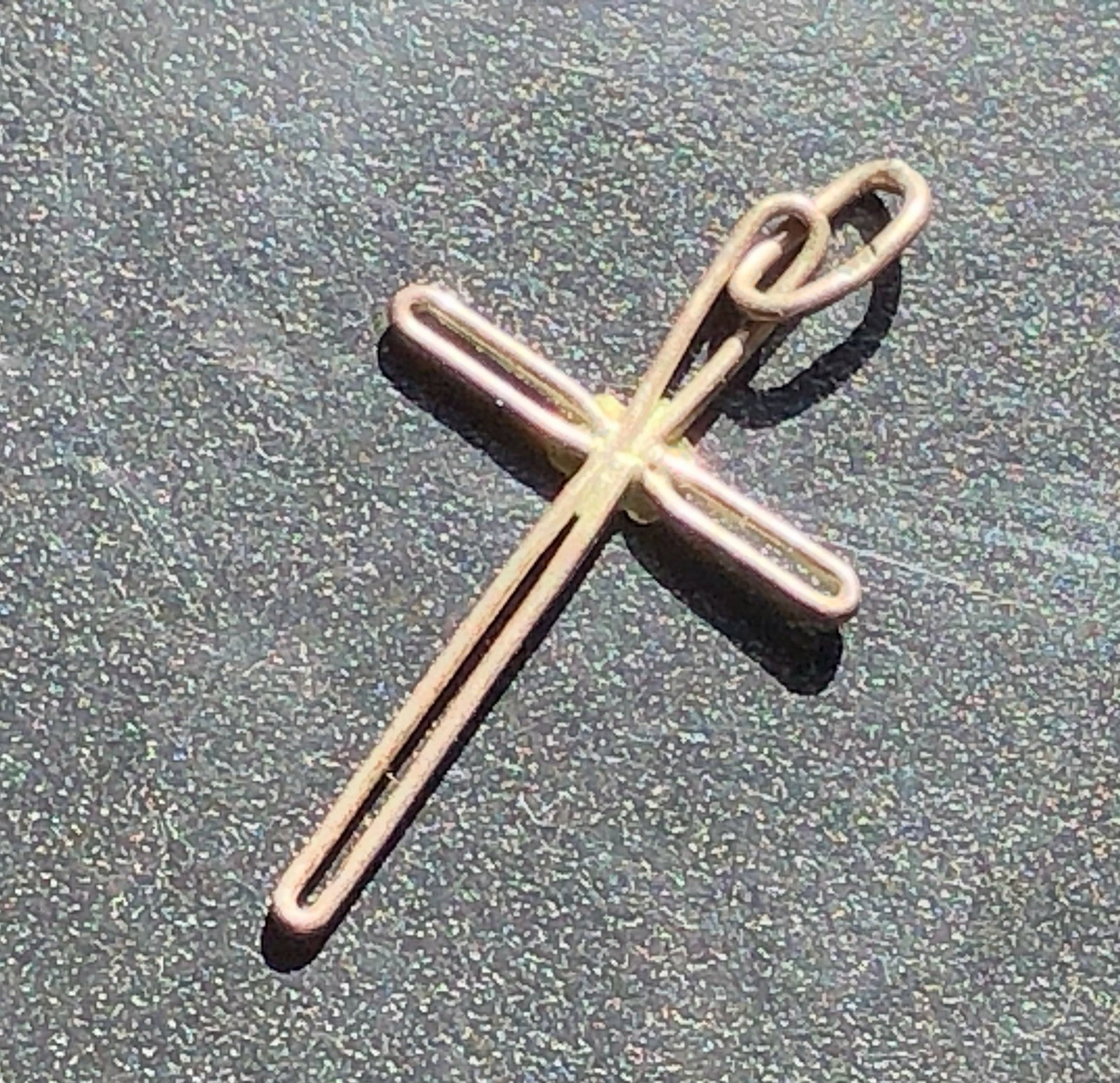 Slender Silver Cross Pendant: Minimalist silver cross pendant formed from slender rounded bars and fitted with a simple suspension loop, showing light surface wear.