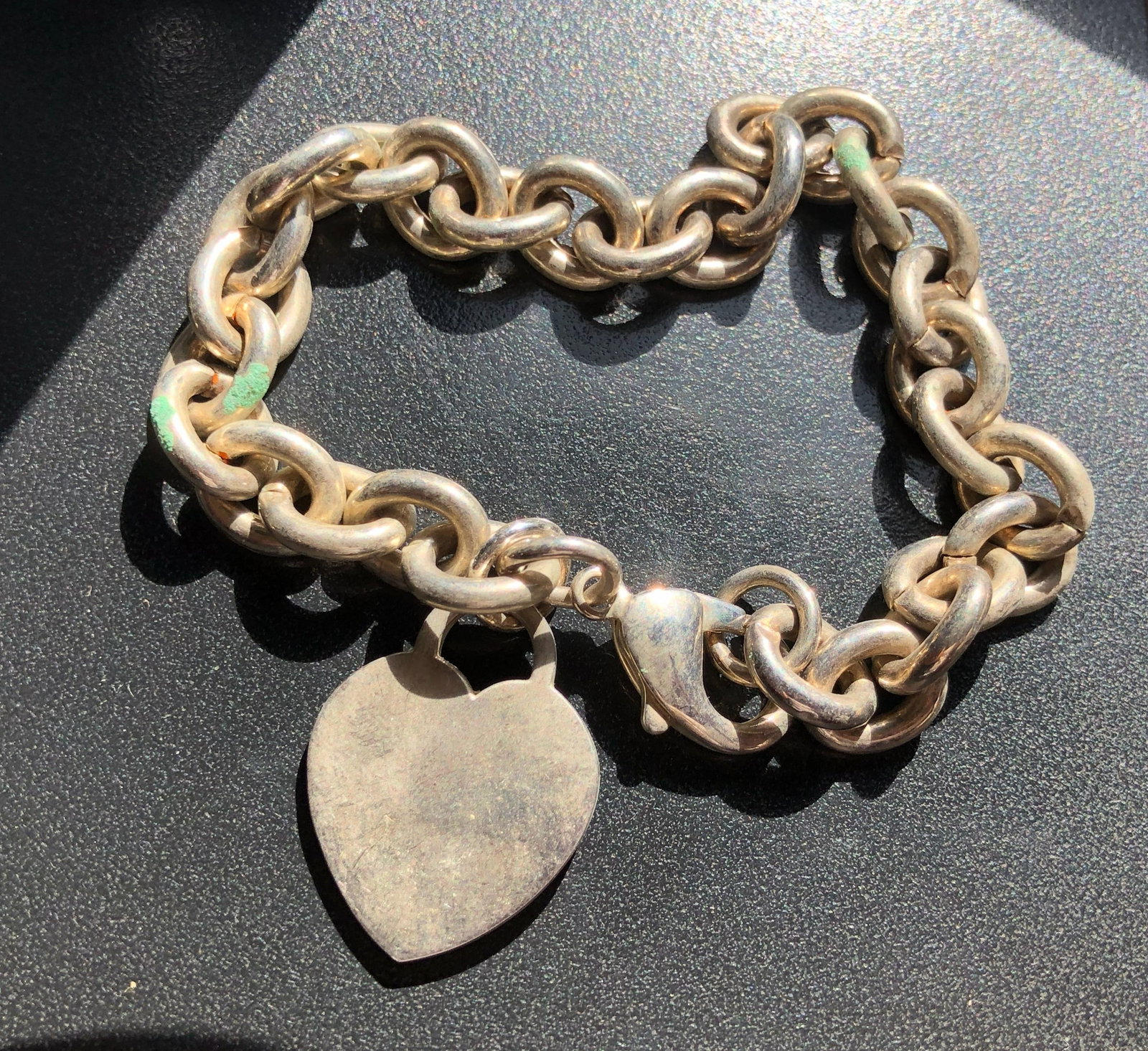Silver-Tone Heart-Tag Chain Bracelet: Chunky silver-tone round-link bracelet with a lobster-claw clasp and plain heart-shaped tag, showing surface wear and patina consistent with use.