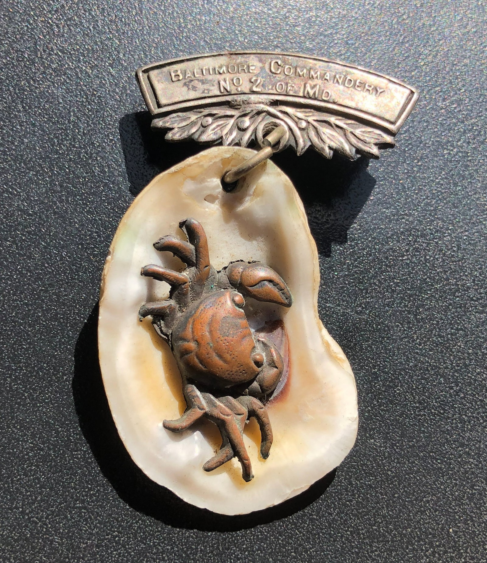 Baltimore Commandery Oyster-Shell Crab Badge with Silver Bar: Novelty badge or brooch featuring a raised crab mounted on a natural oyster shell beneath a silver bar marked ?Baltimore Commandery No. 2,? with age and metal content unconfirmed.