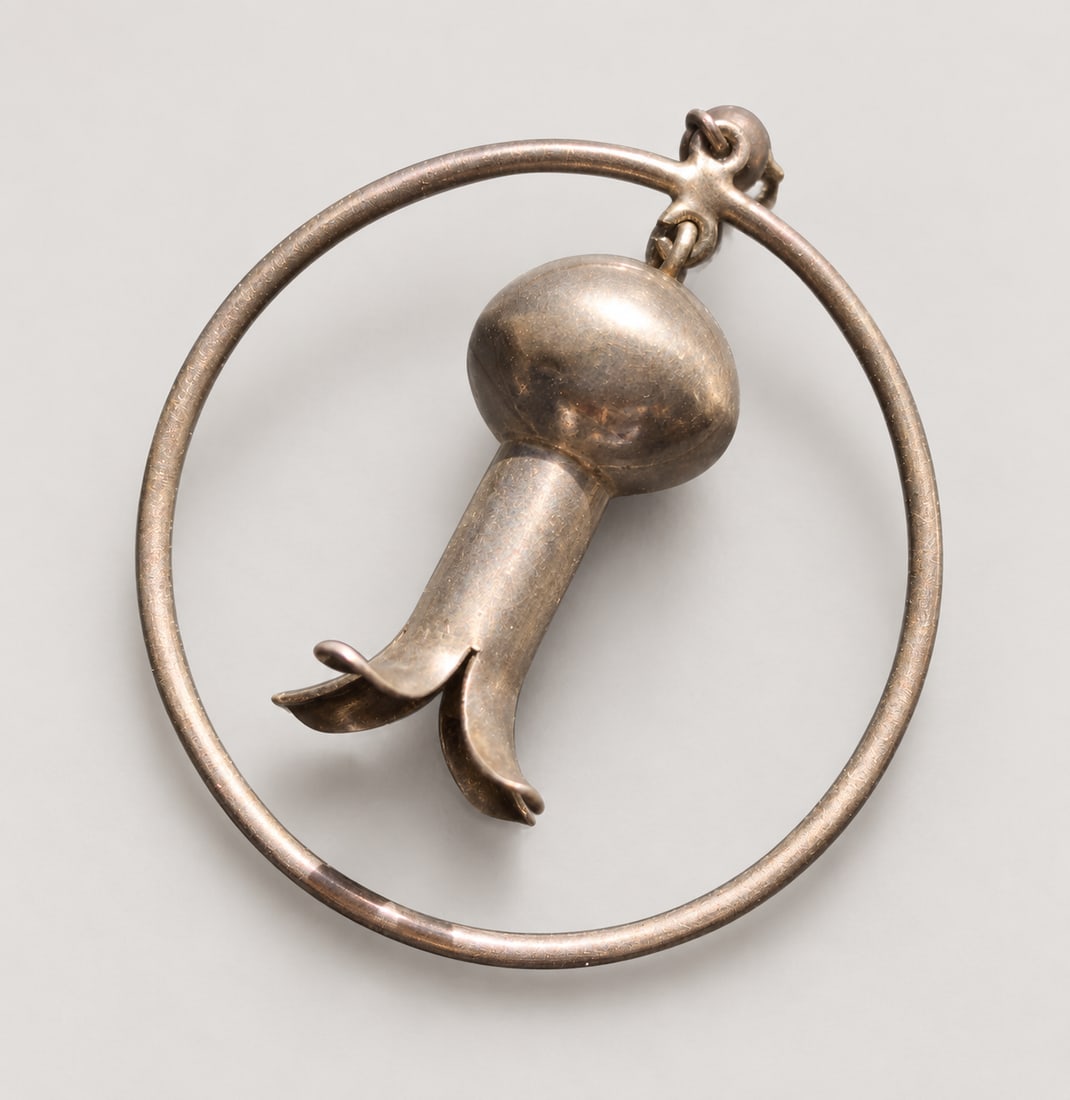 Sculptural Flower-in-Hoop Silver Pendant: A sculptural Silver pendant or charm featuring a stylized drooping flower suspended within a circular frame
