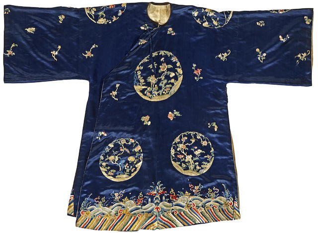 A woman's embroidered blue silk informal robe: A woman's embroidered blue silk informal robe Late Qing dynasty Cut with a right side opening, embroidered in white and polychrome threads with flowering branch and garden rock roundels interspersed w