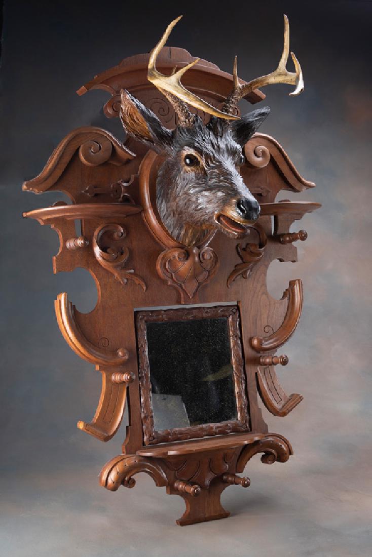 An elaborately carved antique, walnut Victorian hanging: An elaborately carved antique, walnut Victorian hanging Hat Rack, with large Black Forest Style carved wooden deer head at crest with real buck horn antlers and red glass eyes. Rack measures 4 ft. tal