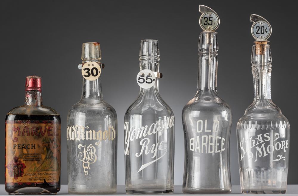 Collection of five Saloon Bar Bottles, four are: Collection of five Saloon Bar Bottles, four are advertising Liquor, in white overlay letters, Silas Moore, Old Barbee, Yemassee Rye, Old Ringold. A vintage unopened Bottle of Marbel Brand Peach Liquor