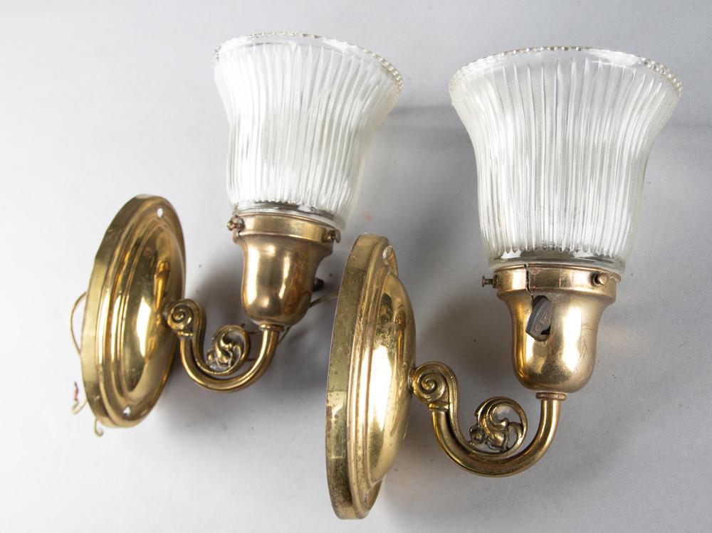 A matching pair of brass Wall Sconces with reeded: A matching pair of brass Wall Sconces with reeded hollow pane shades. WILL BE SOLD AS ONE .