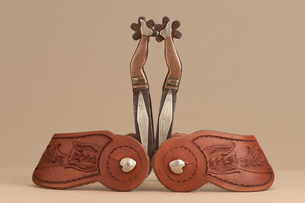 Pair of early gal leg, single mounted Spurs attributed to D. Boone, with long diamond shaped silver: Pair of early gal leg, single mounted Spurs attributed to D. Boone, with long diamond shaped silver overlay on heel bands, small heart buttons, mounted with a pair of lightly tooled two piece floral s