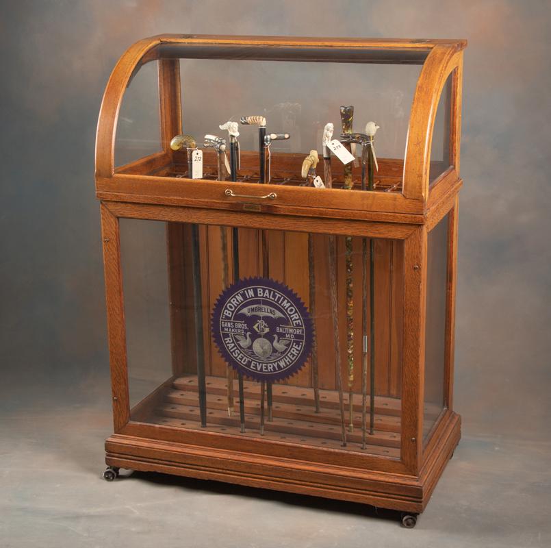 Antique oak, curved glass country store Cane & Umbrella Case, circa 1900. Case is marked "The Oscar: Antique oak, curved glass country store Cane & Umbrella Case, circa 1900. Case is marked "The Oscar Onken Co., Makers of Umbrellas, Coat Racks and Tables, Cincinatti, O." Case was manufactured to hold