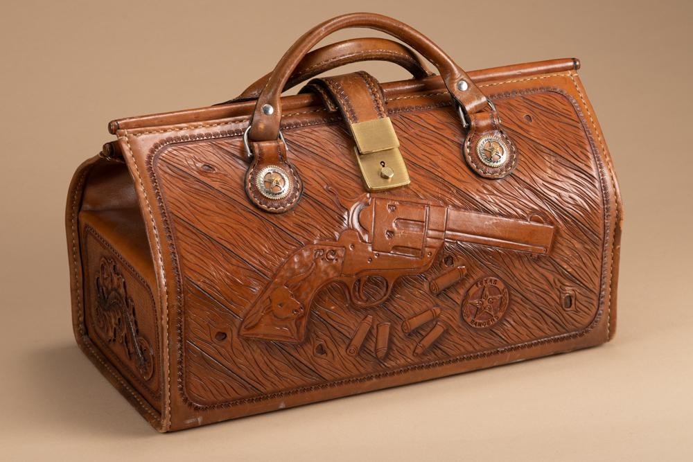 Custom tooled Carry Bag with heavy leather handles, made by D.C. Bear Co., marked inside "Made for: Custom tooled Carry Bag with heavy leather handles, made by D.C. Bear Co., marked inside "Made for Paul Chapman", 16" long x 9 1/2" tall x 8 1/2" wide, fancy tooling on all four sides . Front side has