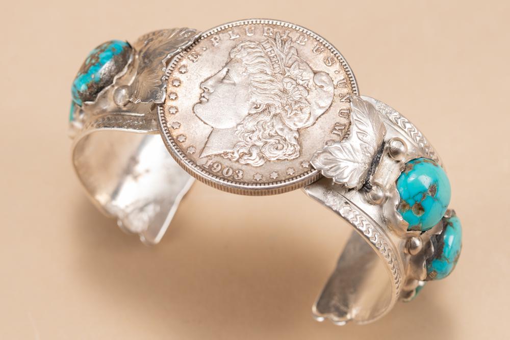 Juan C. Zuni marked silver and turquoise Cuff, mounted with a 1903 U.S. silver dollar in center: Juan C. Zuni marked silver and turquoise Cuff, mounted with a 1903 U.S. silver dollar in center and has 6 polished turquoise stones.