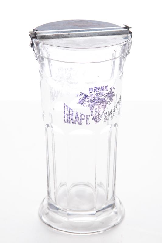 Vintage pressed glass Straw Holder advertising "Drink Grape Smash" with folding silver lid, measures: Vintage pressed glass Straw Holder advertising "Drink Grape Smash" with folding silver lid, measures 9 1/2" T x 5" diameter. BUDDY KING COLLECTION