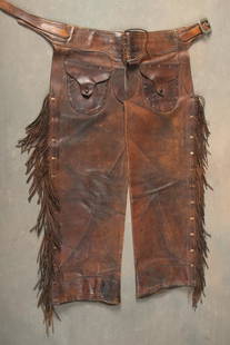 Pair of vintage Stove Pipe Chaps with heavy fringed border, outside pockets with leather buttons,: Pair of vintage Stove Pipe Chaps with heavy fringed border, outside pockets with leather buttons, maker marked on belt "Gary ______, Calgary ________". Chaps and fringe are in good condition, leather