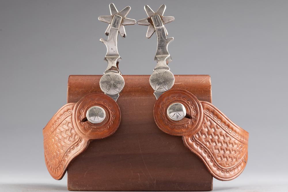 Pair of "McChesney" marked single mounted Spurs (Nocona Period), with raised engraved conchos on: Pair of "McChesney" marked single mounted Spurs (Nocona Period), with raised engraved conchos on heel bands, nickel plated, showing some flaking on left hand spur. Mounted with a pair of basket weave 