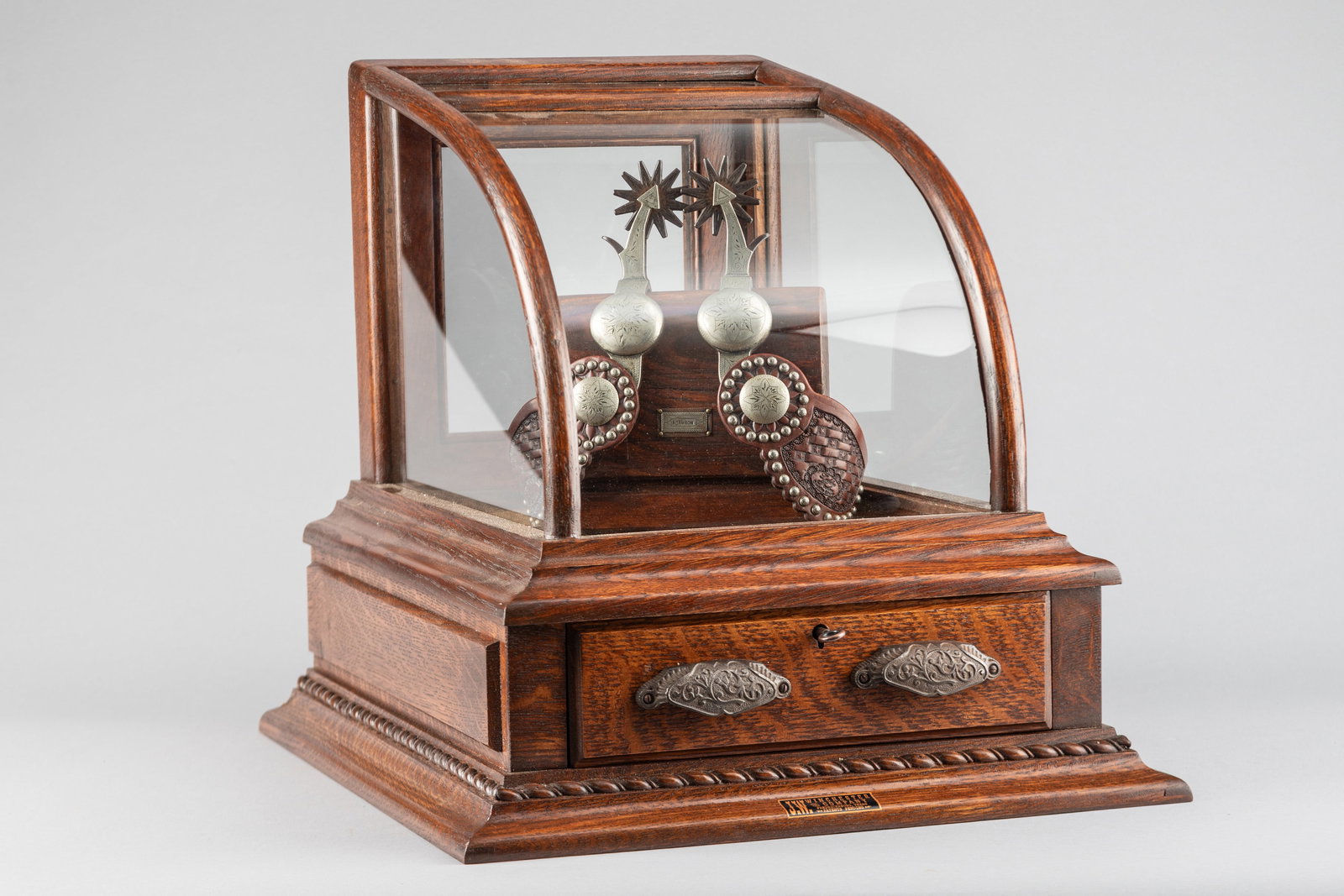 "J.W. Winchester" marked, table model oak Display Case with curved glass front, locking drawer in: "J.W. Winchester" marked, table model oak Display Case with curved glass front, locking drawer in skirt and single door rear entry. Measures 17 1/4" W x 19 1/2" D x 17 1/2" T, sold with key.