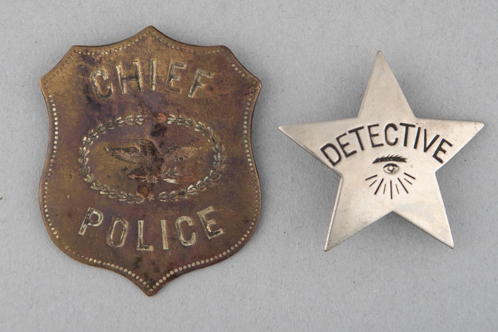 This lot consists of two Badges: (1) Chief of Police Shield Badge with Eagle, 2 1/16" x 1 3/4",: This lot consists of two Badges: (1) Chief of Police Shield Badge with Eagle, 2 1/16" x 1 3/4", missing pin. (2) Detective stock Badge, 5-point star, 1 3/4" across points, turn of the century. These t