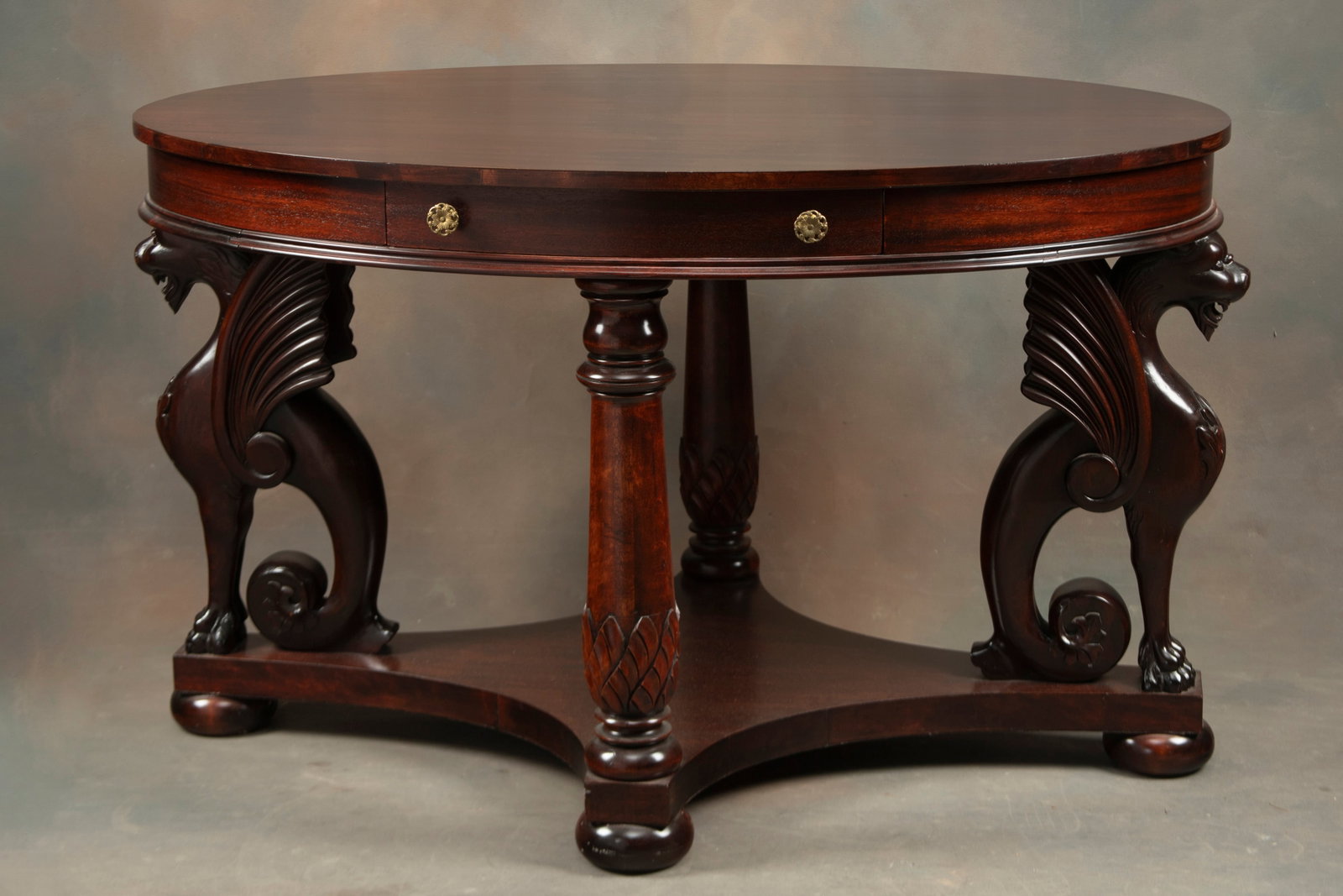 Antique Mahogany Oval Library Table, circa 1900-1910, with fully carved winged griffins supporting: Antique Mahogany Oval Library Table, circa 1900-1910, with fully carved winged griffins supporting top that measures 48" L x 32" across, with drawered skirt. Heavy stretcher on bun feet, measures 29" 