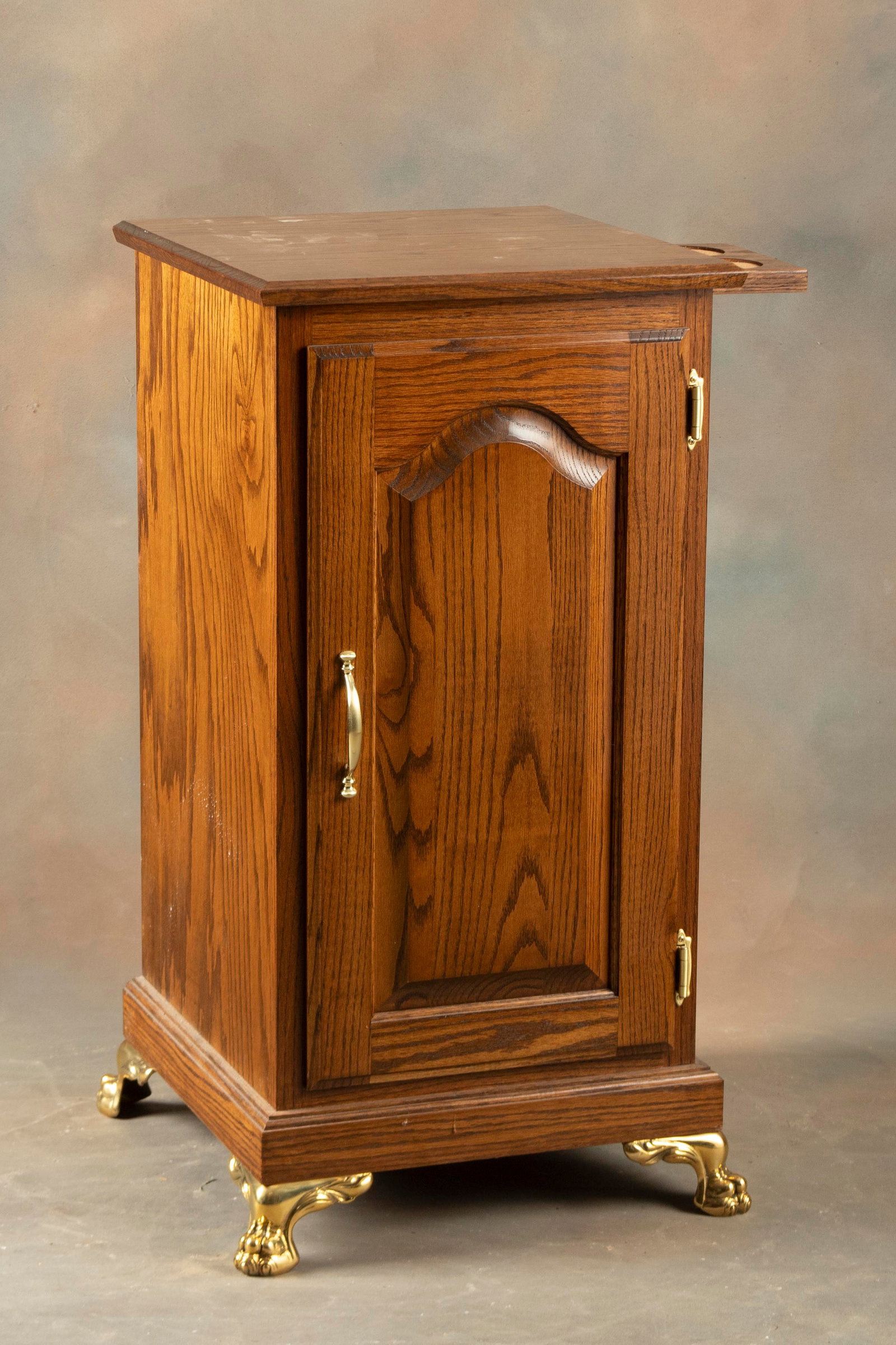 Decorative oak single door Slot Machine Stand on brass feet, measures 34" T x 17 1/4" W x 17 1/4" D: Decorative oak single door Slot Machine Stand on brass feet, measures 34" T x 17 1/4" W x 17 1/4" D with unique pull out drink holder. Very good finish and condition. THE BUDDY KING COLLECTION.