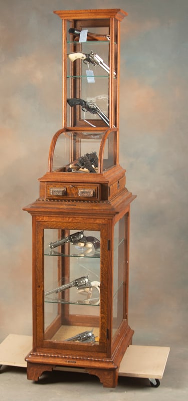 Very unique "J.W. Winchester" marked two-piece quarter sawn oak, floor model Showcase in excellent: Very unique "J.W. Winchester" marked two-piece quarter sawn oak, floor model Showcase in excellent finish and condition. The lower unit measures 18 3/4" W x 23 1/2" D x 34 3/4" T with locking door. Th
