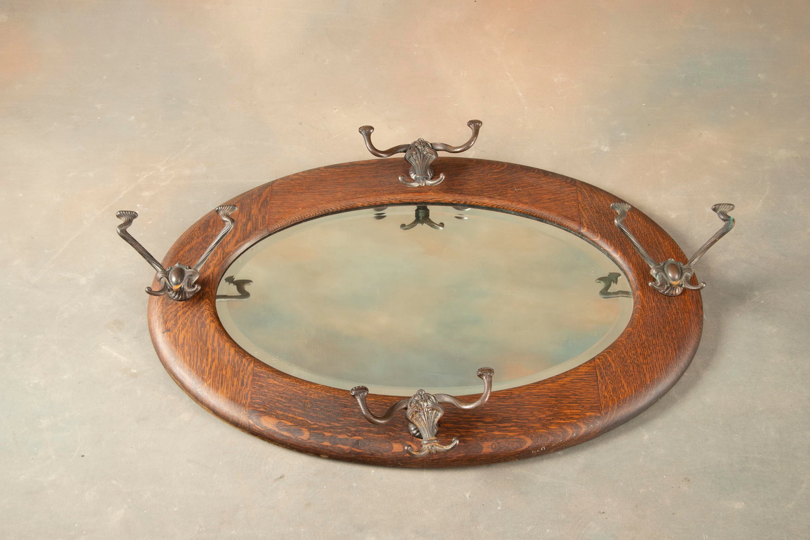 Antique quarter sawn oak oval Hat Rack Hanging Mirror in original finish with four fancy cast iron: Antique quarter sawn oak oval Hat Rack Hanging Mirror in original finish with four fancy cast iron hooks. Mirror measures 31" W x 21" T.