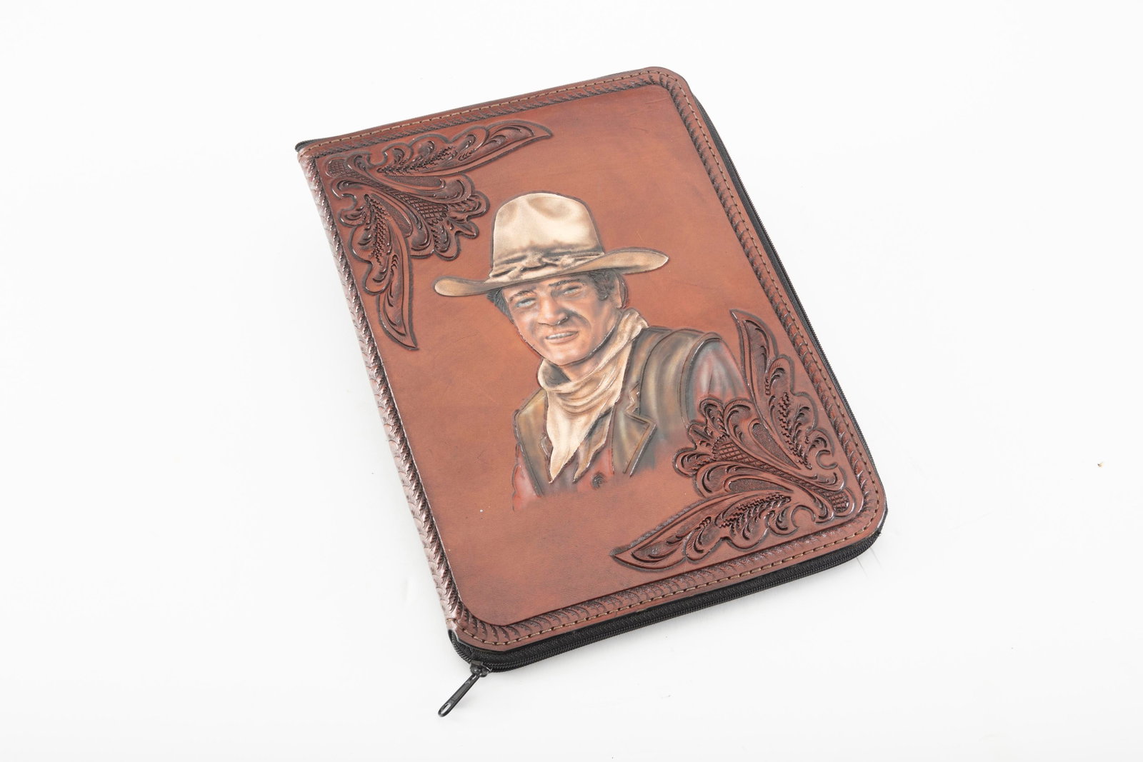 Beautifully hand tooled leather, zippered Folder, measures 13 1/2" x 10". Tooled on front is bust of: Beautifully hand tooled leather, zippered Folder, measures 13 1/2" x 10". Tooled on front is bust of John Wayne and floral carved circle star on back. Near pristine condition. THE LATE PAUL CHAPMAN ES