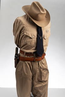 Mannequin dressed in Law Enforcement Uniform to include dress belt, gun belt marked "El Paso: Mannequin dressed in Law Enforcement Uniform to include dress belt, gun belt marked "El Paso Saddlery" with replica automatic fire arm, khaki shirt that has mother of pearl buttons, matching