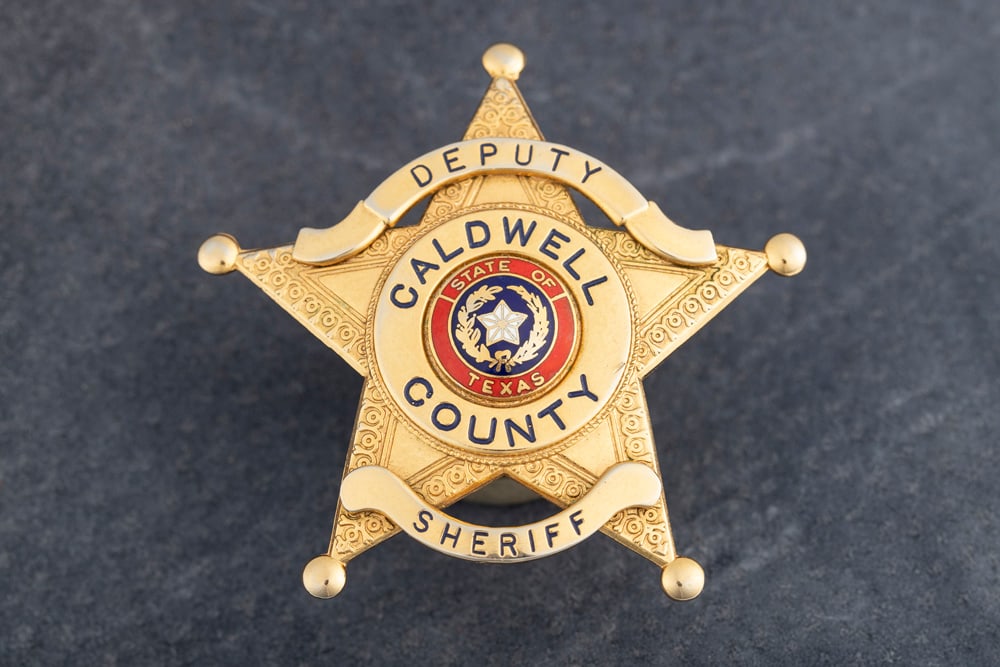 Gold tone “DEPUTY / CALDWELL / COUNTY / SHERIFF?? marked 5-point Ball Star Badge with red and: Gold tone “DEPUTY / CALDWELL / COUNTY / SHERIFF” marked 5-point Ball Star Badge with red and blue enamel “State of Texas” center Seal, nicely detailed with two applied panels. Badge is