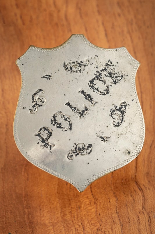 Stock “POLICE?? marked silver tone Shield Badge with ticking around edge, circus lettering with: Stock “POLICE” marked silver tone Shield Badge with ticking around edge, circus lettering with lots of enamel loss. Measures 2 1/2” T x 2” W has pin with “C” catch. No Hall