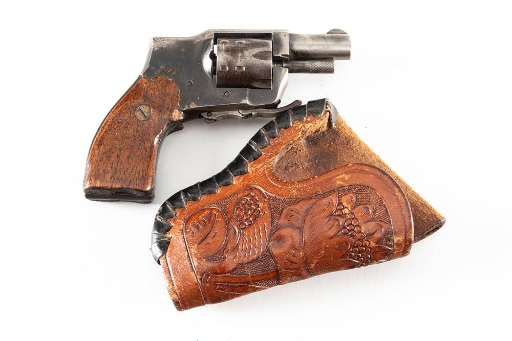 Baby Hammerless, Ejector Model Revolver, .22 Short caliber, SN NV, 1" barrel with folding trigger.: Baby Hammerless, Ejector Model Revolver, .22 Short caliber, SN NV, 1" barrel with folding trigger. Sold with a floral tooled miniature Holster. Appears to have handmade wooden grips. (MODERN) THE BUDD