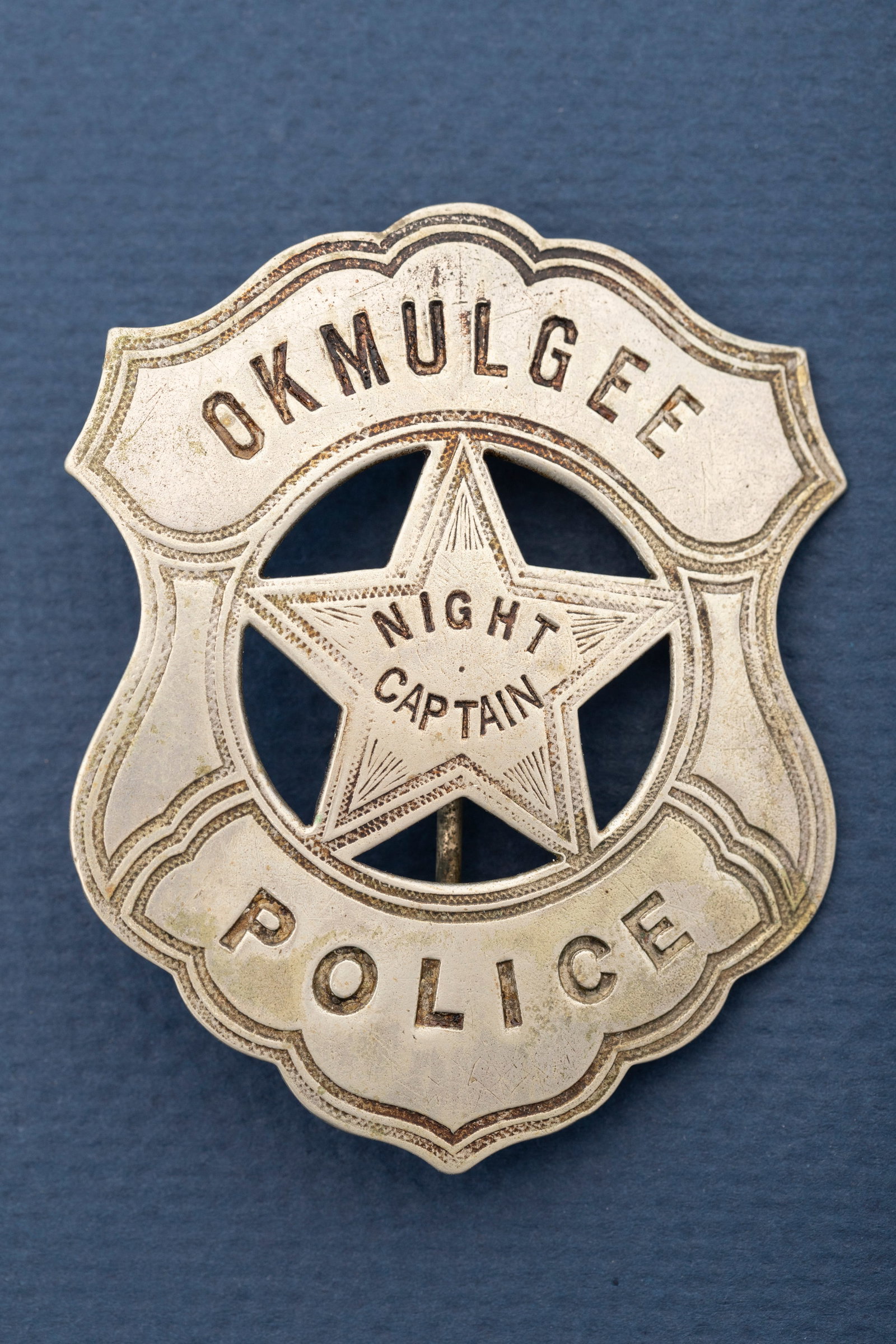Very nice vintage Shield Badge with 5-point cut out star center, marked "Okmulgee Police/Night: Very nice vintage Shield Badge with 5-point cut out star center, marked "Okmulgee Police/Night Captain", excellent detail. Hallmarked by famous maker "C.D. Reese/ 57 Warren St. N.Y.", has pin with lar
