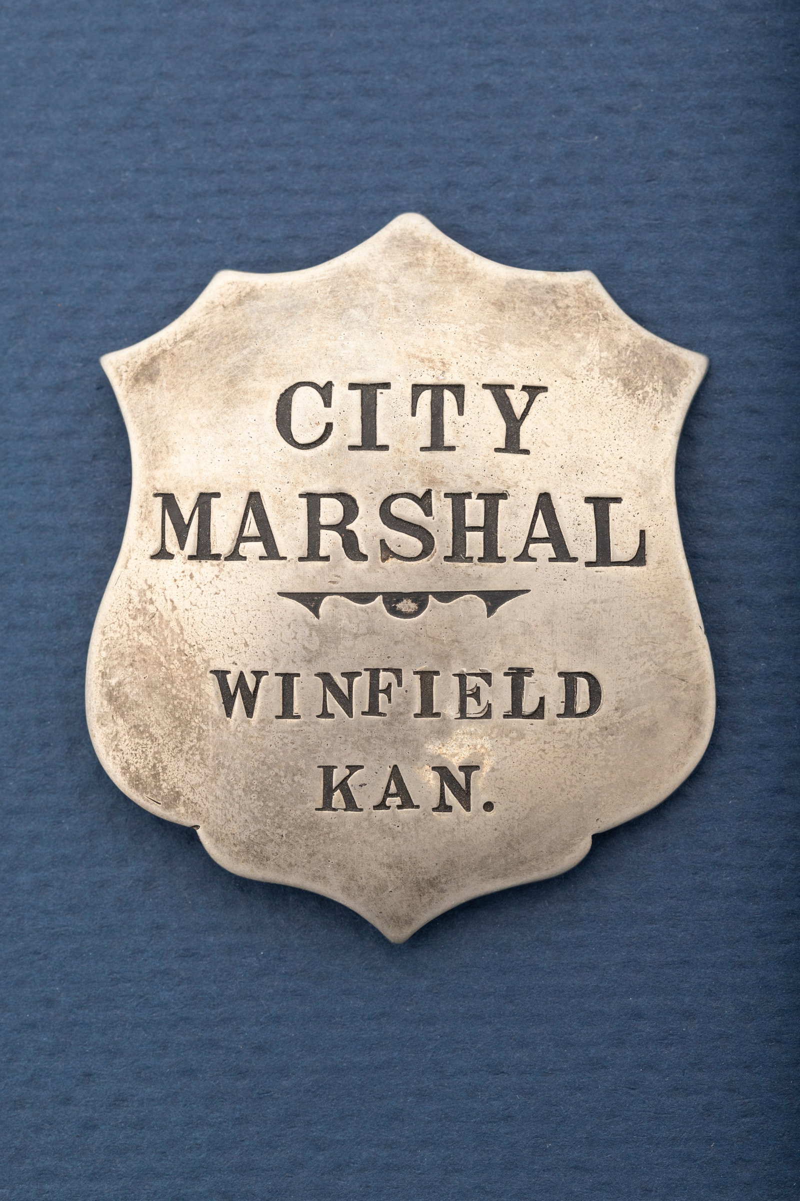 Fantastic vintage silver tone Shield Badge, marked "City Marshal/Winfield Kan.", great patina with: Fantastic vintage silver tone Shield Badge, marked "City Marshal/Winfield Kan.", great patina with old small "T" pin and very small tongue catch. Measures 2 1/8" T x 1 7/8" W. Estimate $300/500.00. HU