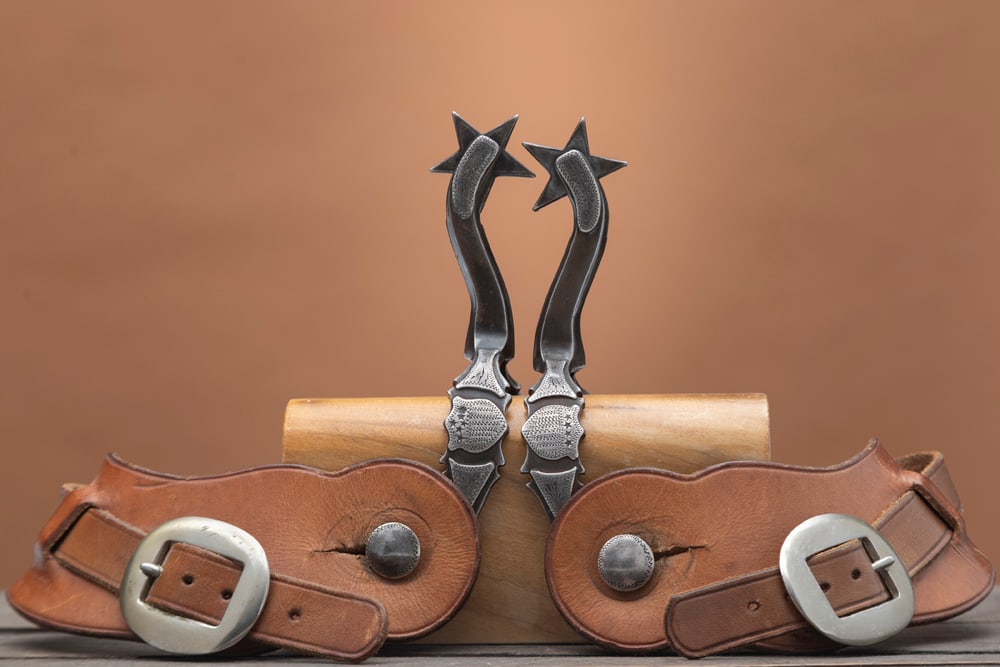 Pair of double mounted Spurs with engraved shield on each side of the heel band, attributed to: Pair of double mounted Spurs with engraved shield on each side of the heel band, attributed to Oklahoma Bit & Spur Maker Louis Bryant, excellent patina and condition. Sold with a pair of 2-piece leath