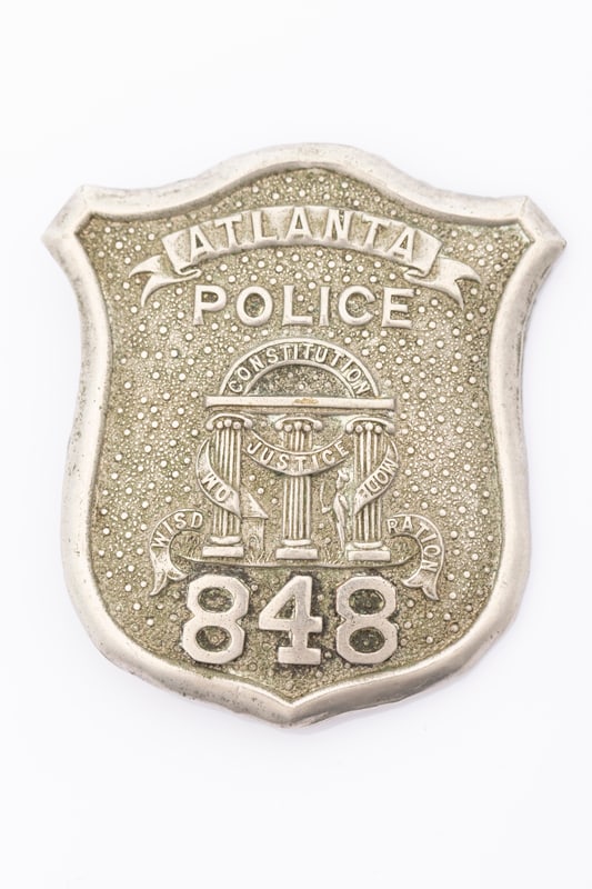 Vintage silver tone Shield Badge marked "Atlanta Police / 848", with intricate center design,: Vintage silver tone Shield Badge marked "Atlanta Police / 848", with intricate center design, measures 2 5/8" T x 2 3/8" W, spring pin with tunnel catch. Estimate $150/275.00. HUTCHESON COLLECTION.