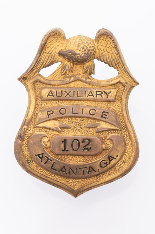 Vintage Shield Cap Badge with eagle crest marked "Auxiliary / Police / 102 / Atlanta". Most of the: Vintage Shield Cap Badge with eagle crest marked "Auxiliary / Police / 102 / Atlanta". Most of the plating is missing, screw post and cap are intact, measures 2 1/2" T x 1 7/8" W. Estimate $100/150.00