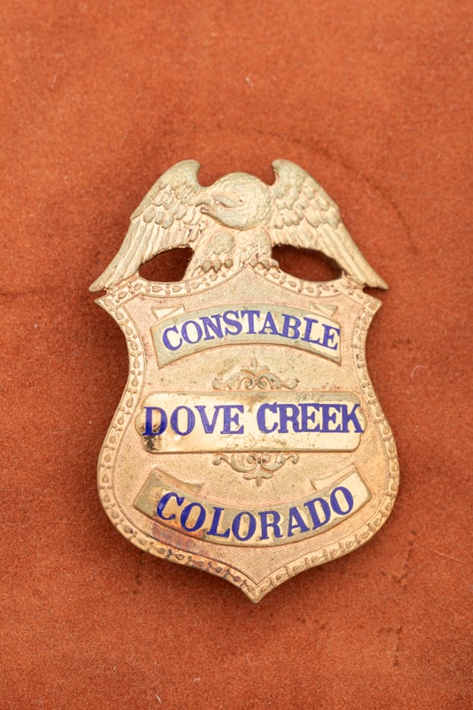 Vintage eagle crest Shield Badge marked "Constable / Dove Creek / Colorado", measures 2 1/2" T x 1: Vintage eagle crest Shield Badge marked "Constable / Dove Creek / Colorado", measures 2 1/2" T x 1 3/4" W. Badge has lots of wear with heavy pin and Burgess catch. Estimate $150/350.00. HUTCHESON COLL