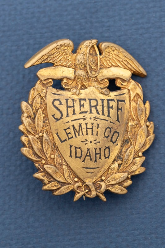 Vintage and very heavy Shield Badge with eagle crest marked "Sheriff / Lemhi Co./ Idaho". Back is: Vintage and very heavy Shield Badge with eagle crest marked "Sheriff / Lemhi Co./ Idaho". Back is hallmarked "S.A. French / N.Y.", measures 2 1/8" x 1 3/4" W, has spring pin with "C" catch. Estimate $