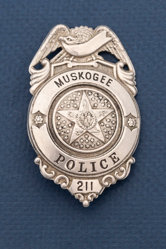 Beautiful vintage Shield Badge with eagle crest marked "Muskogee / Police / 211", with a greatly: Beautiful vintage Shield Badge with eagle crest marked "Muskogee / Police / 211", with a greatly decorated 5-point raised star as center seal. Back is hallmarked "K.C. Mo. / Liepsner & Co." with saddl