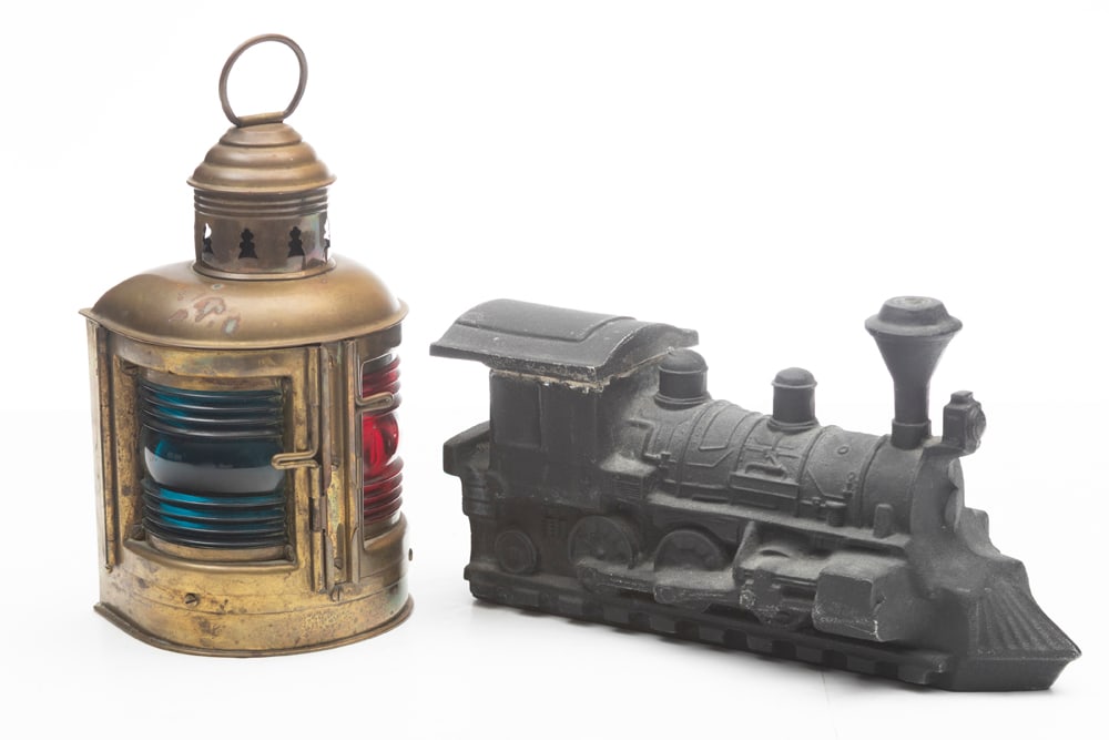 This lot consists of the following two items: (1) A brass Perkins Marine Lamp titled "Perko" with: This lot consists of the following two items: (1) A brass Perkins Marine Lamp titled "Perko" with red and blue glass inserts. 10" T x 5" W. (2) Black metal Train with lift off top, 12" L x 5 1/2" T. W