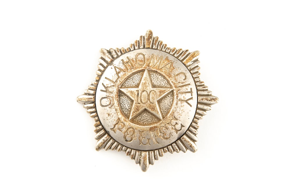 Sunburst shaped vintage Badge marked “OKLAHOMA CITY POLICE?? with “100?? in raised star: Sunburst shaped vintage Badge marked “OKLAHOMA CITY POLICE” with “100” in raised star center. Hallmarked “SACHS-LAWLOR DENVER COLO.” Face of badge is in rough condition with a 