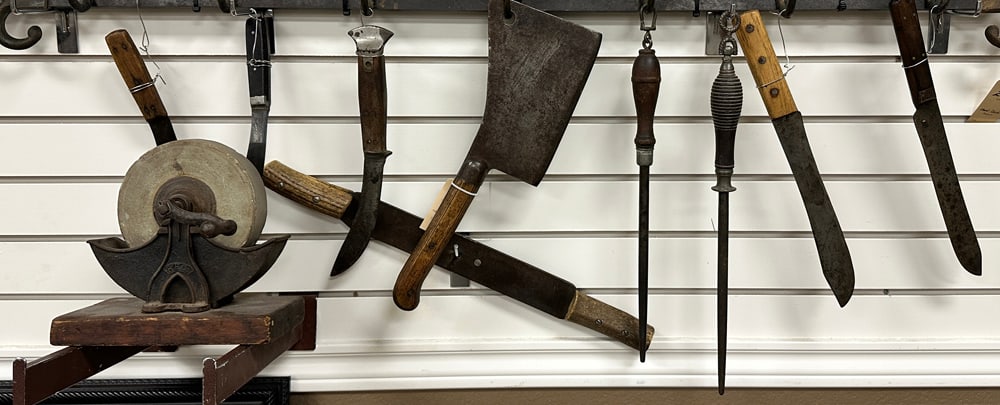 Ten (10) vintage Butcher Tools to include: 1 large Meat Cleaver, 2 shapening Hones, 6 Butcher: Ten (10) vintage Butcher Tools to include: 1 large Meat Cleaver, 2 shapening Hones, 6 Butcher Knives, and 1 small Sharpening Wheel. These items would go well with the previous lot and WILL SELL AS ONE
