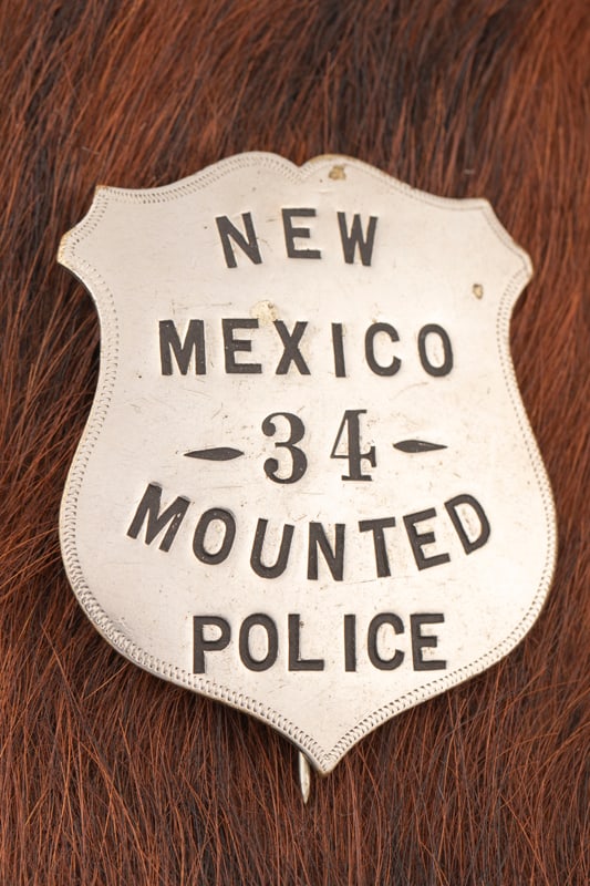 Vintage “NEW MEXICO 34 MOUNTED POLICE?? marked Shield Badge with ticking around the edge, has: Vintage “NEW MEXICO 34 MOUNTED POLICE” marked Shield Badge with ticking around the edge, has tongue catch and measures 2 ¼” T x 1 7/8” W. The Lee Hutcheson Collection.