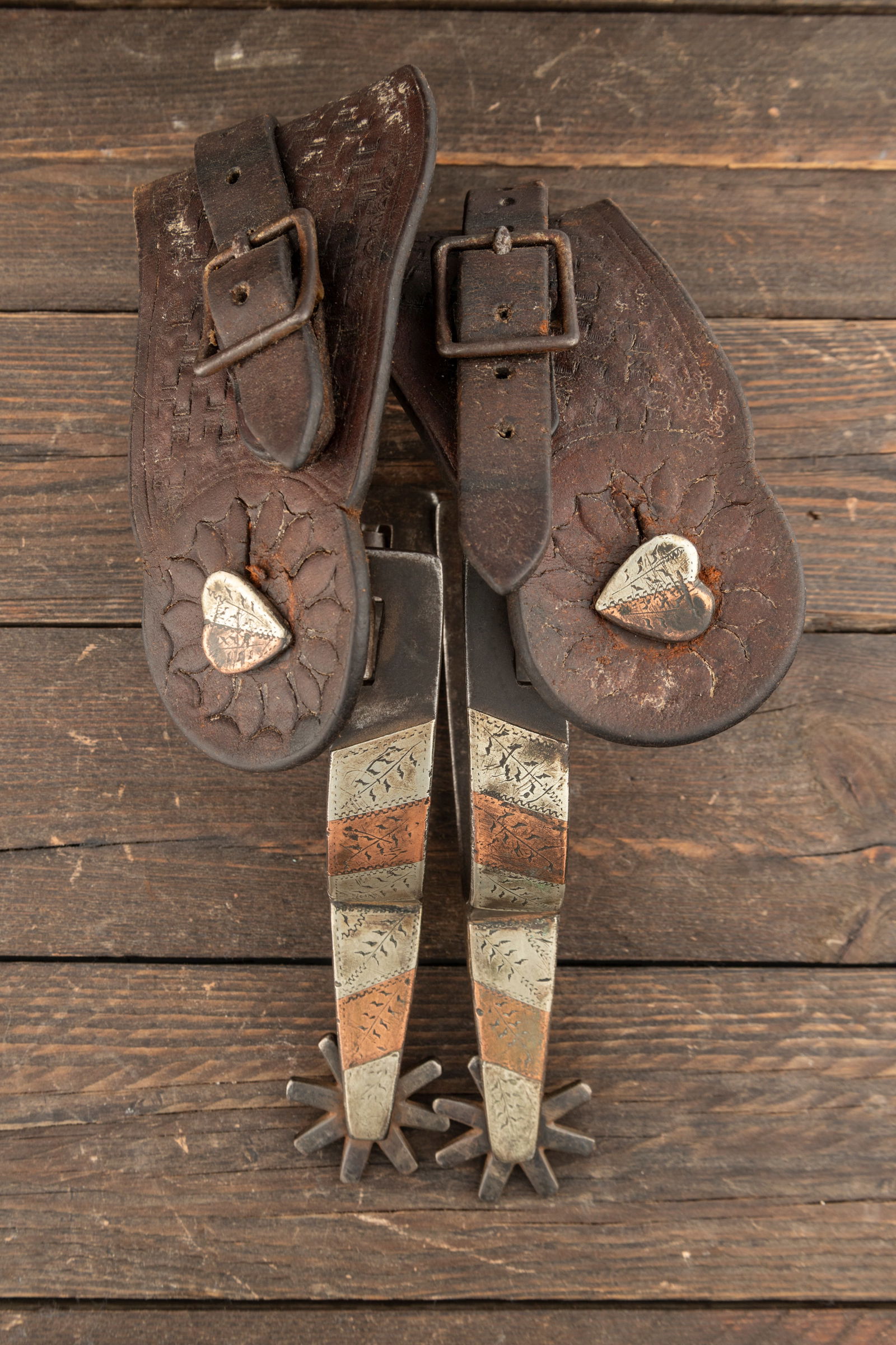 Pair of "J. O. Bass, Tulia, Tex." marked single mounted Spurs, #1074, in engraved copper and silver: Pair of "J. O. Bass, Tulia, Tex." marked single mounted Spurs, #1074, in engraved copper and silver and split heart swing buttons. Sold with vintage two-piece straps. Maples Estate.